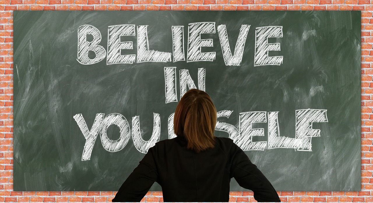 Women Standing in front of sign that says 'Believe in Yourself'